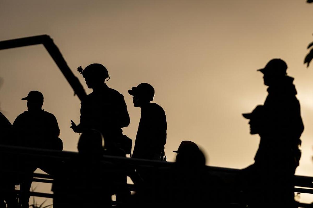 Un grupo de rescatistas apuran el atardecer en una zona de derrumbes.