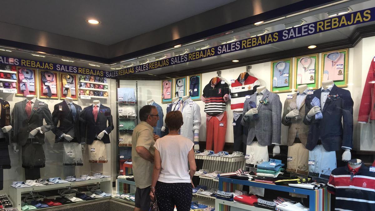 Una pareja mira artículos en una tienda de ropa en época de rebajas.