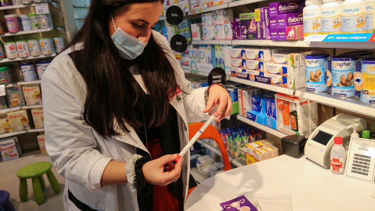 Una farmacéutica de la Farmacia Marta Bosch, en El Prat de Llobregat, muestra el Kit de autodiagnóstico del virus del papiloma humano.