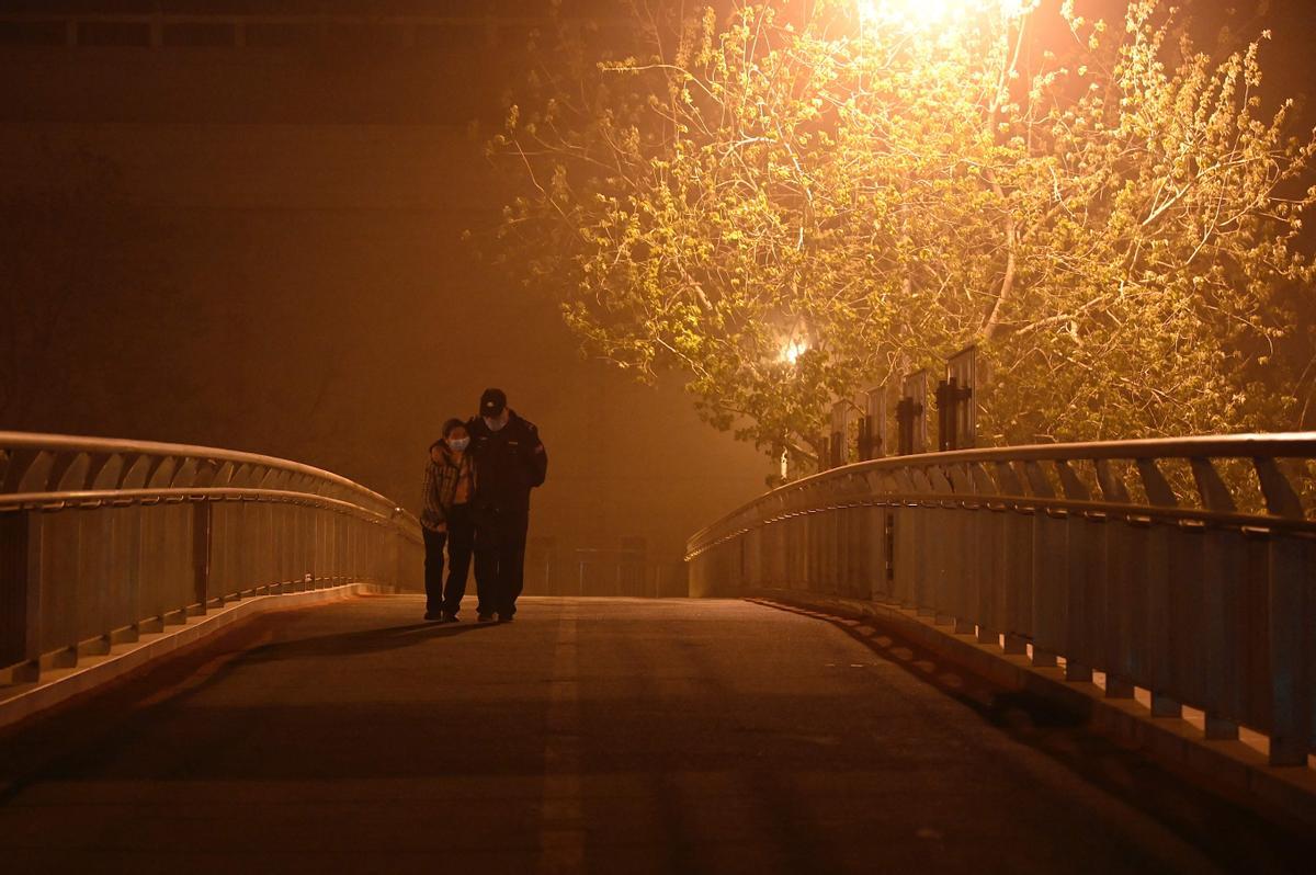 Ciudadanos por las calles de Pekín, durante un episodio de una fuerte tormenta de arena.