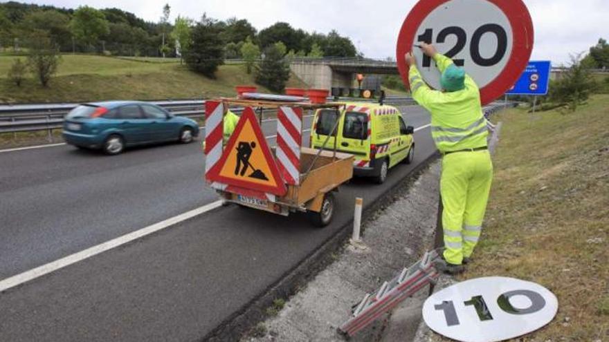 Un operario retira una pegatina de 110 km/h, durante el anterior cambio del límite de velocidad a 120.