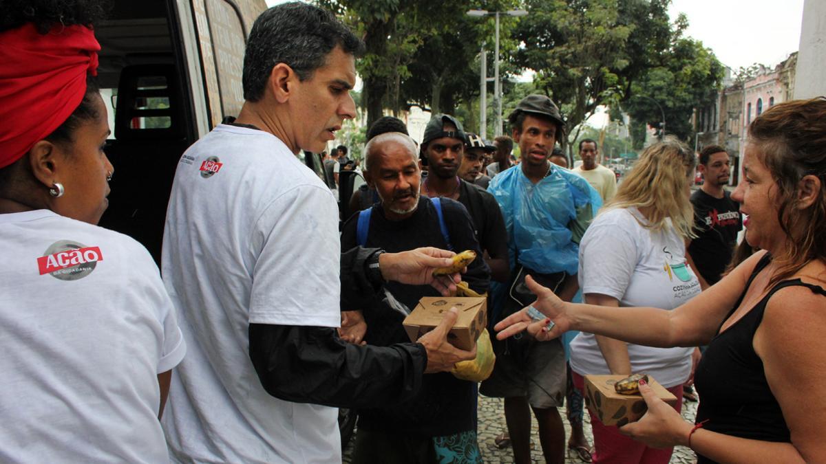 Voluntarios de Ação pela Cidadania reparten 100 raciones de comida en el centro de Rio de Janeiro.