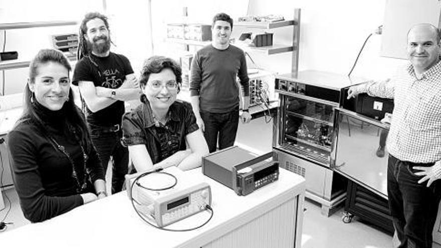 Por la izquierda, Bango, Anseán, González, Antuña y Viera, en el laboratorio de baterías de la Universidad de Oviedo. A la izquierda, un puesto de carga para coches eléctricos. / juan plaza