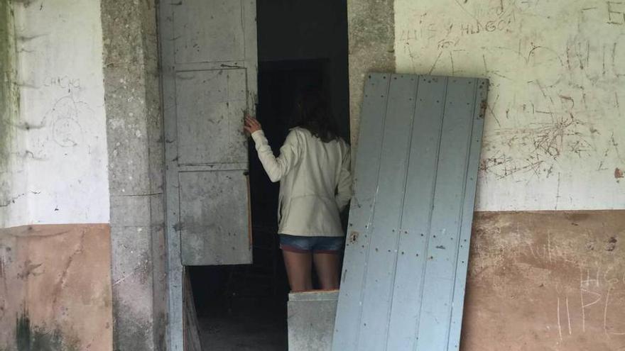 Una vecina observa los daños causados en la puerta de acceso a la escuela de Peruyes, ayer.