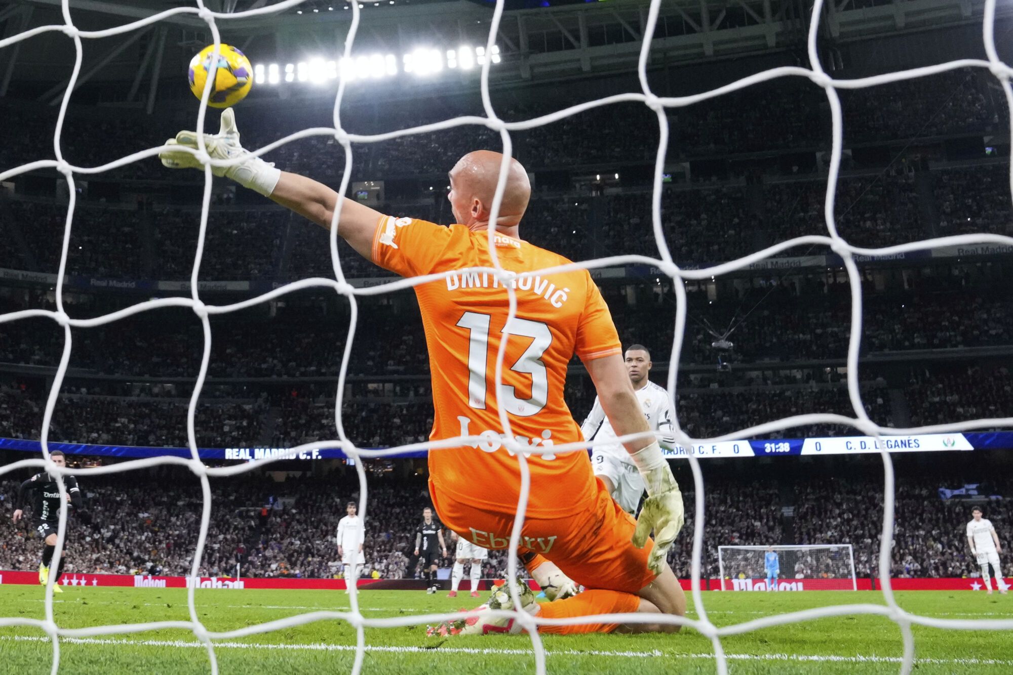 Real Madrid's Kylian Mbappe scores from a penalty kick by Leganes' goalkeeper Marko Dmitrovic during a Spanish La Liga soccer match between Real Madrid and Leganes at the Santiago Bernabeu stadium in Madrid, Spain, Saturday, March 29, 2025. (AP Photo/Manu Fernandez)