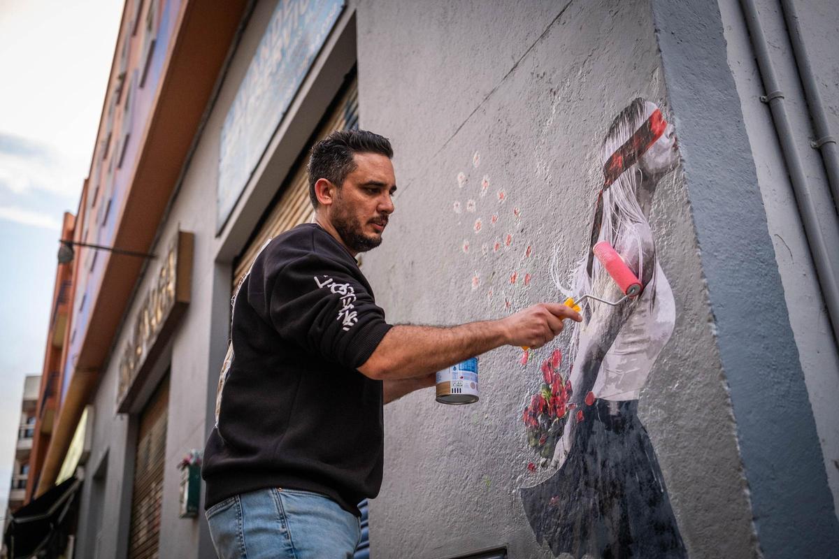 Alberto León pasa cola sobre el mural para fijarlo mejor.