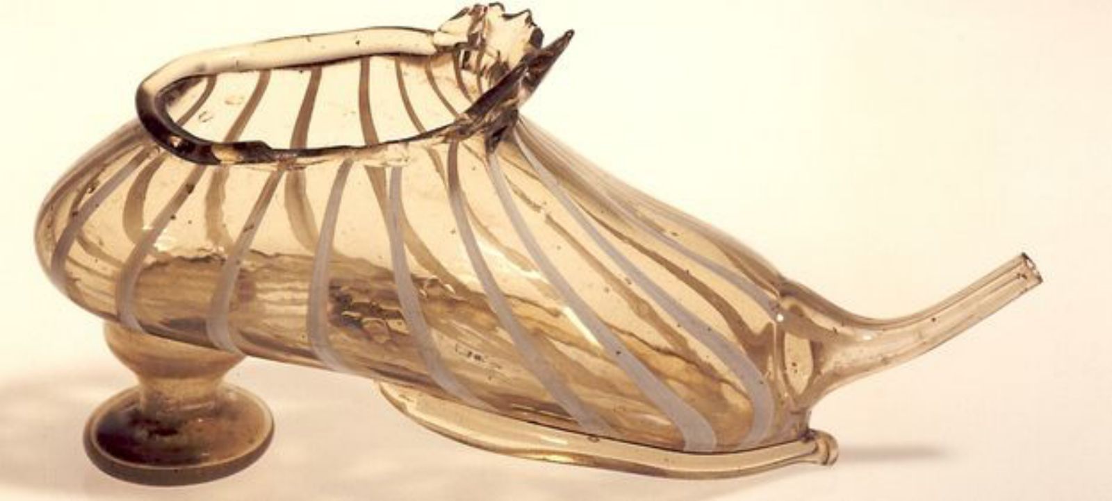 Peça catalana segle XVI-XVII feta de vidre bufat i amb forma de sabata que servia per donar líquids als malalts o infants.