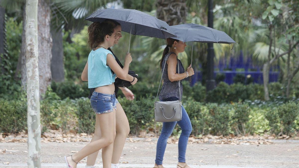Imagen de archivo de personas cobijándose de la lluvia bajo un paraguas.
