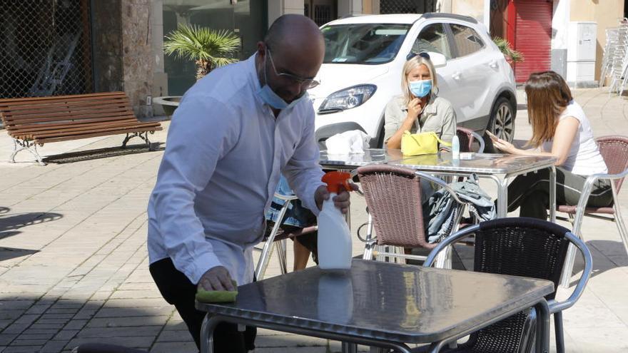Un cambrer desinfectant la taula a la plaça de l&#039;Ajuntament
