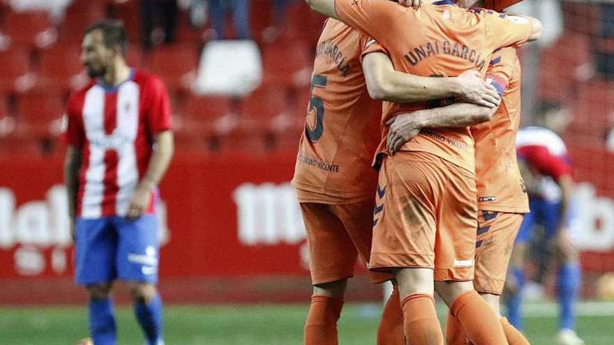 Los jugadores de Osasuna se abrazan, con uno del Sporting, al fondo, cabizbajo.