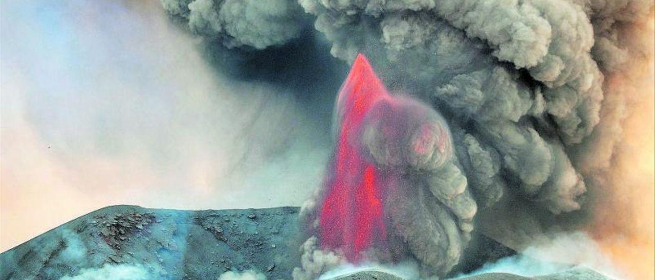 Una pluma de lava incandescente se abre paso entre una nube oscura de ceniza y piroclastos en el volcán de La Palma.