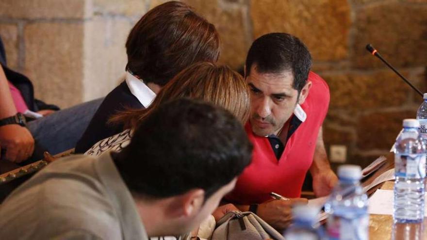 Espiño (dcha.) conversa con sus compañeros durante el pleno extraordinario sobre el SAF.