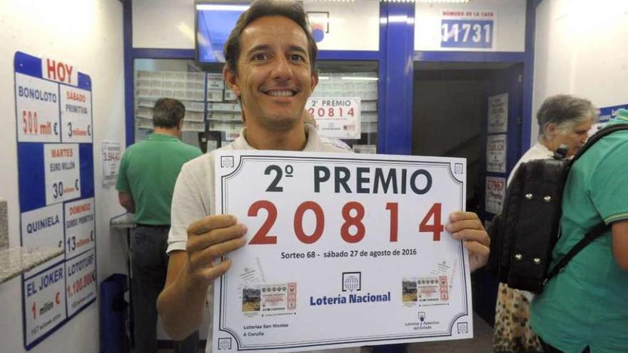 Iván González, con el cartel del segundo premio de la Lotería, en la administración de San Nicolás.