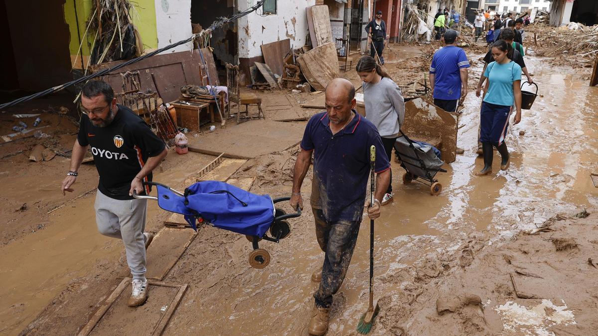 Vecinos cruzan las calles de Paiporta con la compra, en la primera semana después de la catástrofe.