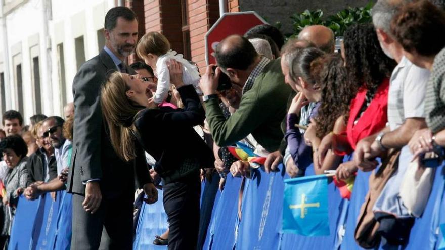 más cercanos que nunca. La Reina coge en brazos a un niño, ante la atenta mirada de Felipe VI, durante su paseo de ayer por las calles de Boal.