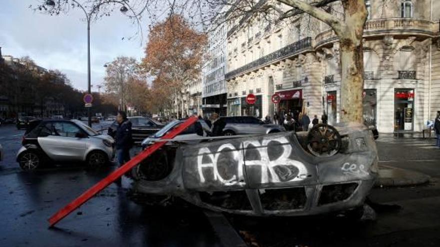 Un cotxe cremat i bolcat al mig del carrer a París.
