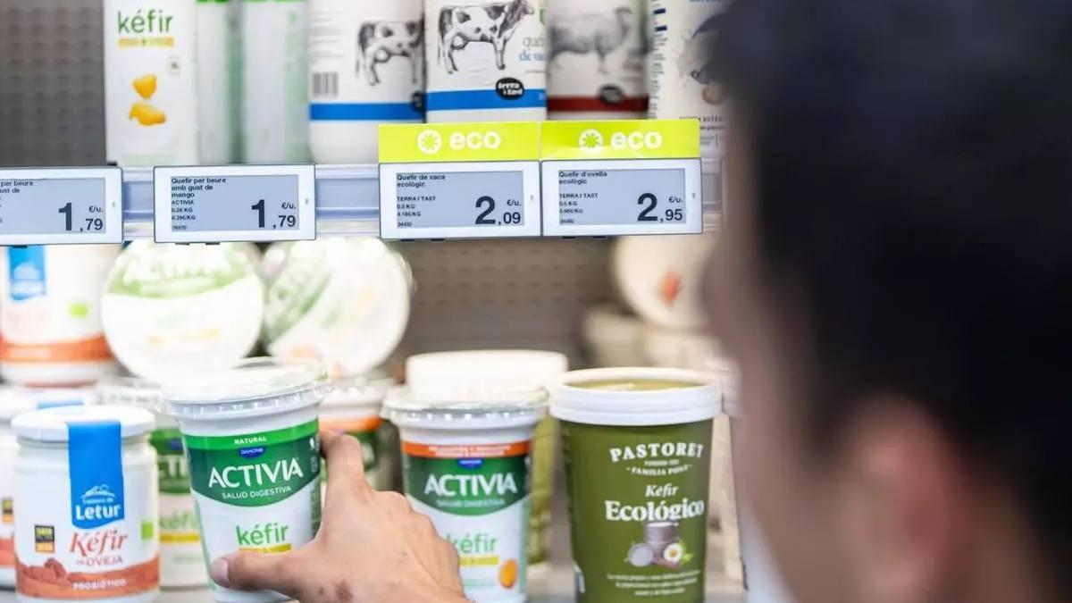 Un home tria un quefir d’una nevera de productes lactis d’un supermercat