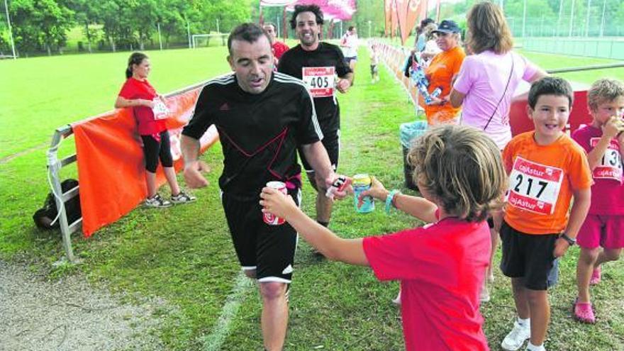 Un niño ofrece bebida a uno de los corredores.