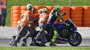 Los comisarios de Cheste ayudan a Valentino Rossi a retirar su Yamaha averiada.