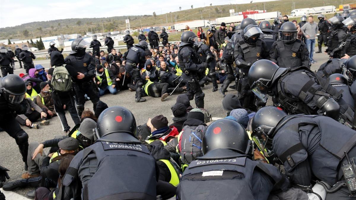 Agentes de la Brimo de los Mossos desalojan por la fuerza la AP-7 a la altura de Figueres.