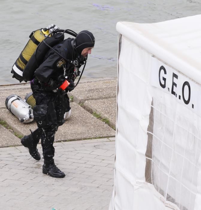 Los especialistas, que necesitan luz natural, trabajan en una zona balizada en un margen del río, apoyados por una lancha de la Policía Nacional, todo ello vigilado por agentes que impiden el acceso a la orilla de la dársena.