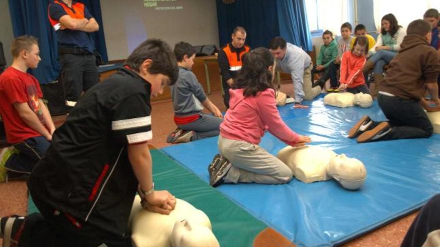 A la izquierda, los alumnos practican la reanimación en muñecos, siguiendo las explicaciones de Mauricio Bogomak, al fondo. A la derecha, los niños, aprendiendo a colocarse.