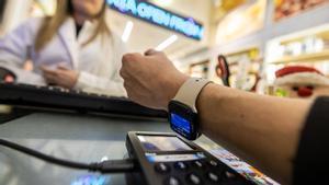 Nuevos sistemas de pago, en un comercios de proximidad, un cliente paga con el reloj