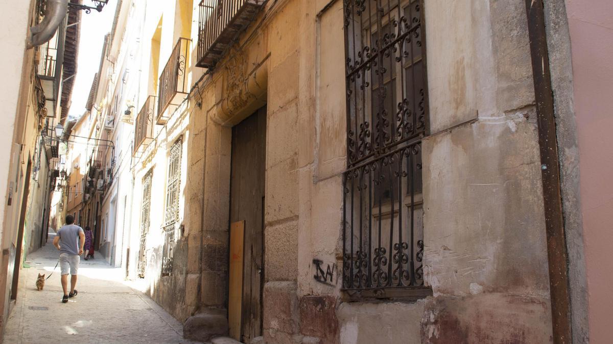 Un hombre pasea al perro por una calle del casco antiguo de Xàtiva.