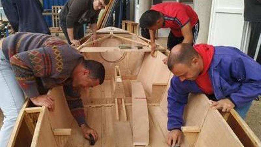 Los estudiantes trabajan en el casco de madera del velero.