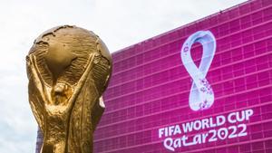 Trofeo de la Copa del Mundo junto a uno de los estadios de Catar 2022.