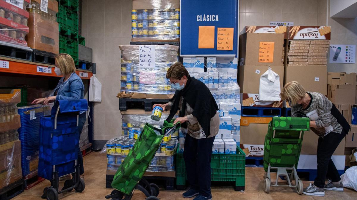 Tres voluntarias de Joventut Antoniana preparan los carros de compra con los alimentos que llevan a los domicilios de los usuarios, este martes.