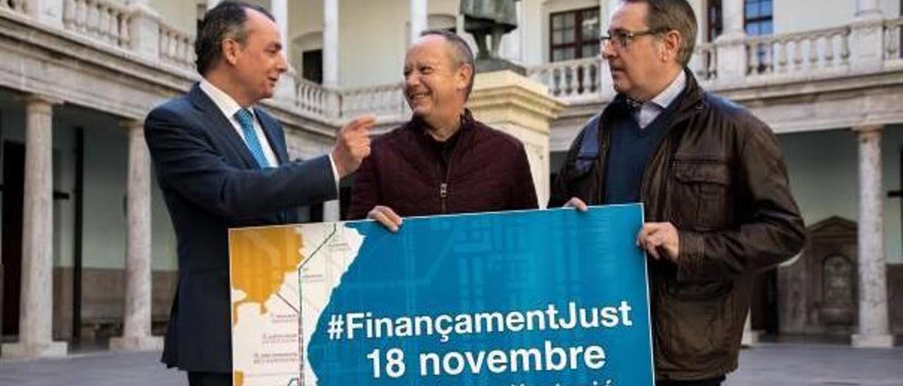 El presidente de la CEV, Salvador Navarro, y los secretarios de CCOO, Arturo León, y UGT, Ismael Saez con el cartel del 18N ayer en la Nau.