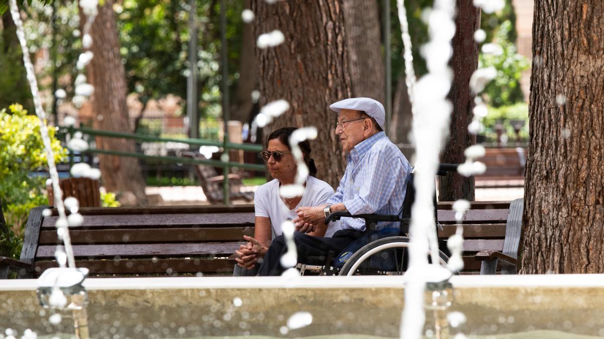 Una mujer y un hombre de avanzada edad descansan al lado de una fuente en el parque Abelardo Sánchez, a 11 de julio de 2023, en Albacete, Castilla-La Mancha (España).