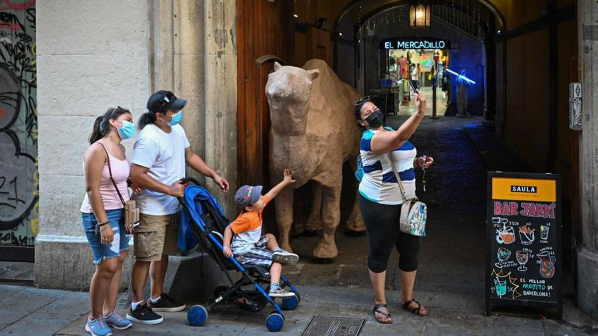 Unos turistas se fotografían con el camello que preside la entrada de las galerías El Mercadillo.