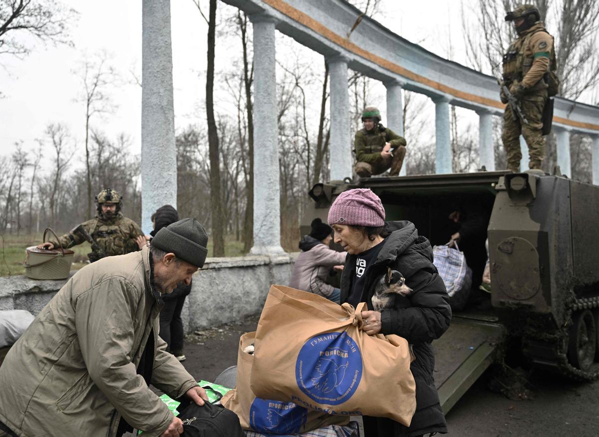 Un grupo de civiles evacuados de Bakhmut cargan pertenencias personales cuando salen de un vehículo blindado de transporte de personal (APC) del ejército ucraniano en Chasiv Yar.