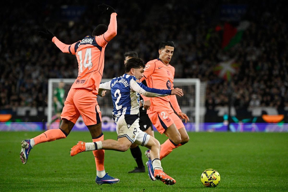 Barcelona's English forward #14 Marcus Rashford and Real Sociedad's Venezuelan defender #02 Jon Aramburu (C) fight for the ball during the Spanish league football match between Real Sociedad and FC Barcelona at Anoeta Stadium in San Sebastian on January 18, 2026. (Photo by ANDER GILLENEA / AFP)