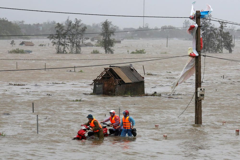 People recover motorbikes from a flooded fields ...