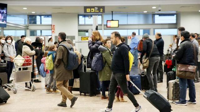 Varios pasajeros recogen sus equipajes en la zona de llegadas del aeropuerto de Peinador. |   // MARTA G. BREA