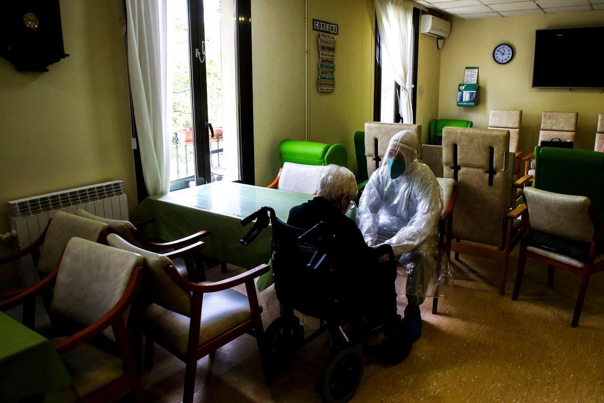 Un voluntario de Open Arms habla en la sala de estar de una residencia de Barcelona con una usuaria.