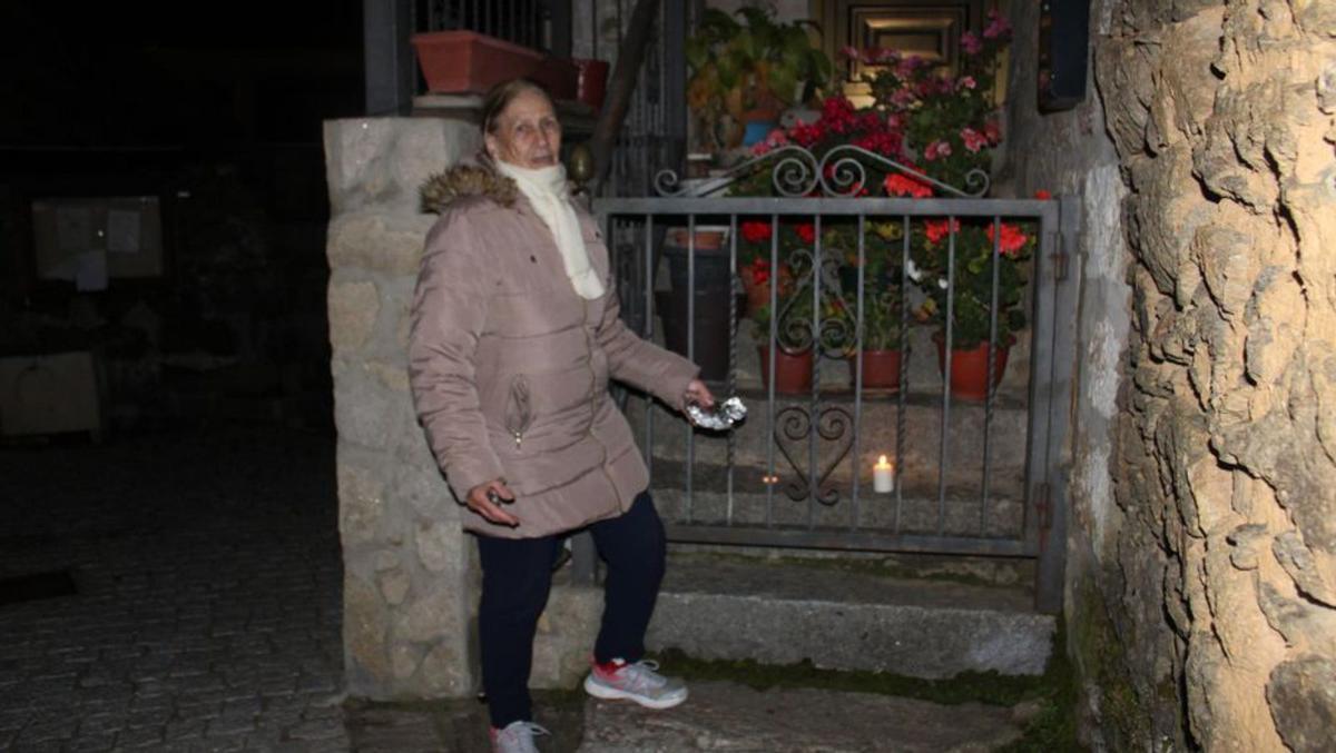 Una mujer coloca una vela en la puerta de una vivienda. | A. S.