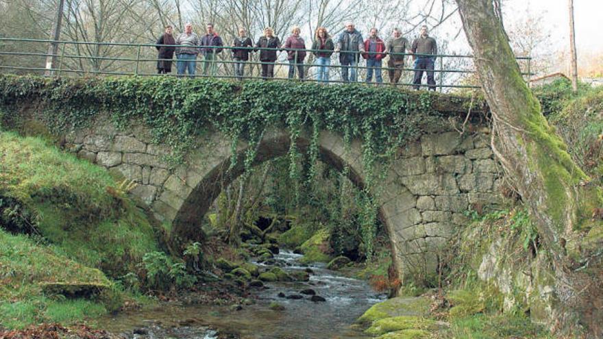 Un grupo de vecinos sobre un puente del río Calvo de Parada de Achas, en A Cañiza.  // D.P.