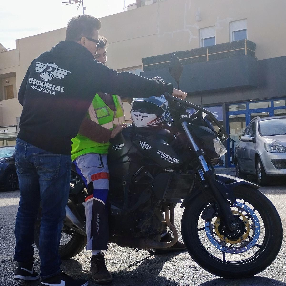 Un profesor de Autoescuela Residencial enseña a un alumno a conducir una moto.