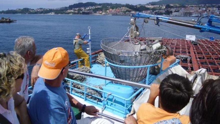 Los turistas asisten al vaciado del mejillón en el barco, transportado por una grúa desde la batea.  // Gonzalo Núñez