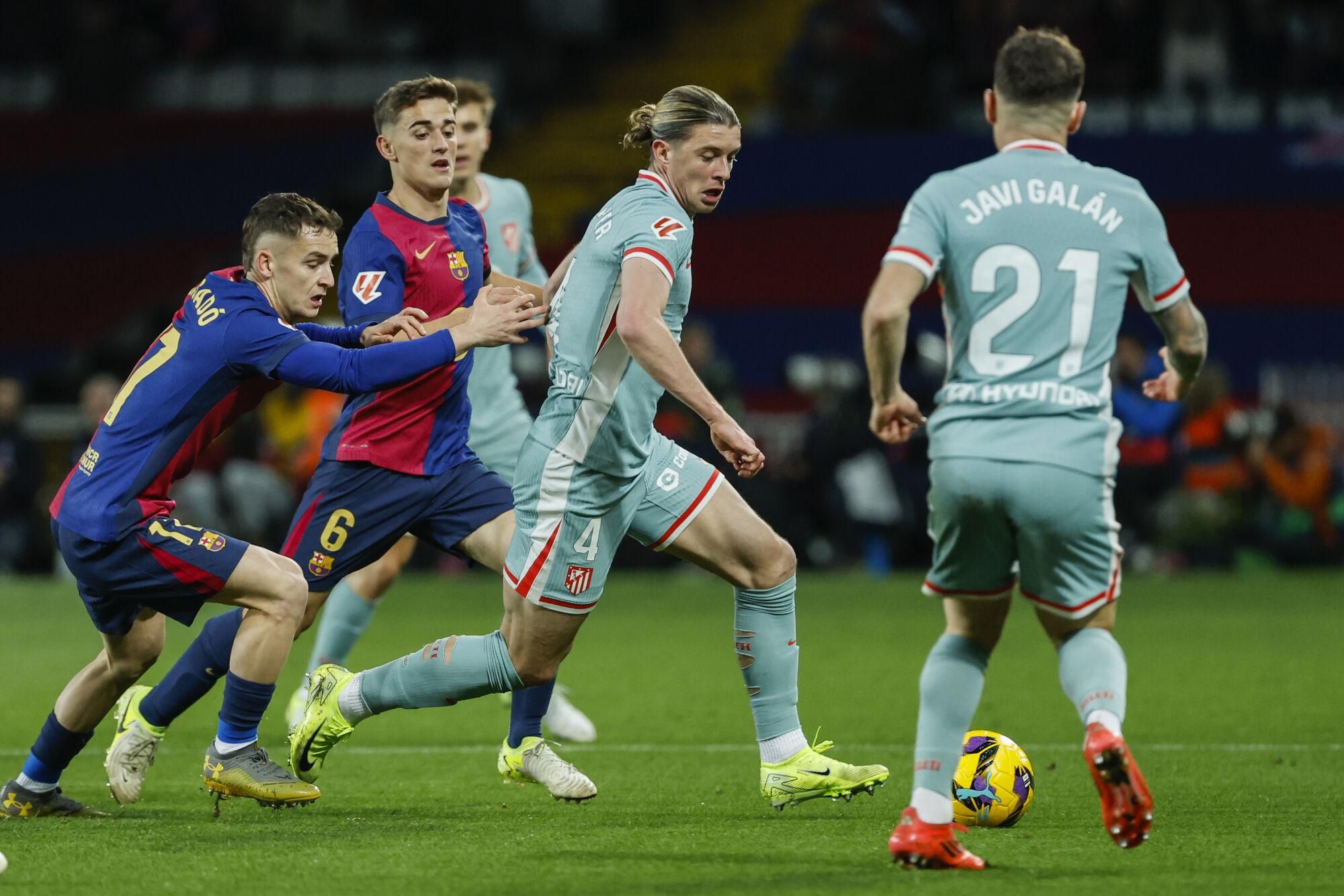 Barcelona's Marc Casado, left, duels for the ball with Atletico Madrid's Conor Gallagher, center, during the Spanish La Liga soccer match between Barcelona and Atletico Madrid at the Lluis Companys Olympic Stadium in Barcelona, Spain, Saturday, Dec. 21, 2024. (AP Photo/Joan Monfort)