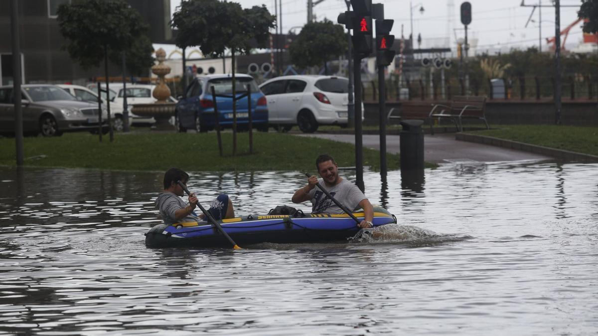 Dos vecinos recorren en lancha las calles de Avilés, tras la inundación que sufrió en 2016.