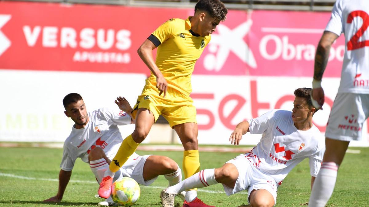 Abde controla el balón entre dos jugadores del Murcia.  