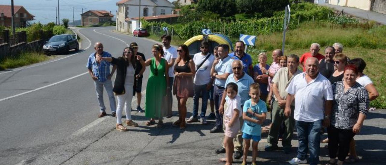 Gallego, de verde, con vecinos ante el vial sin aceras. | G. NÚÑEZ