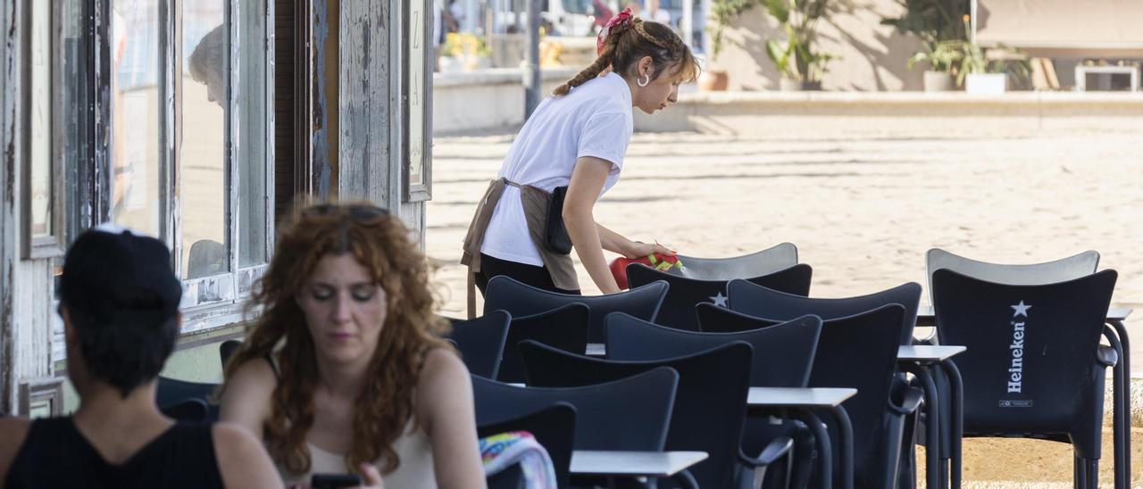 Una camarera recoge una mesa en la playa de València.