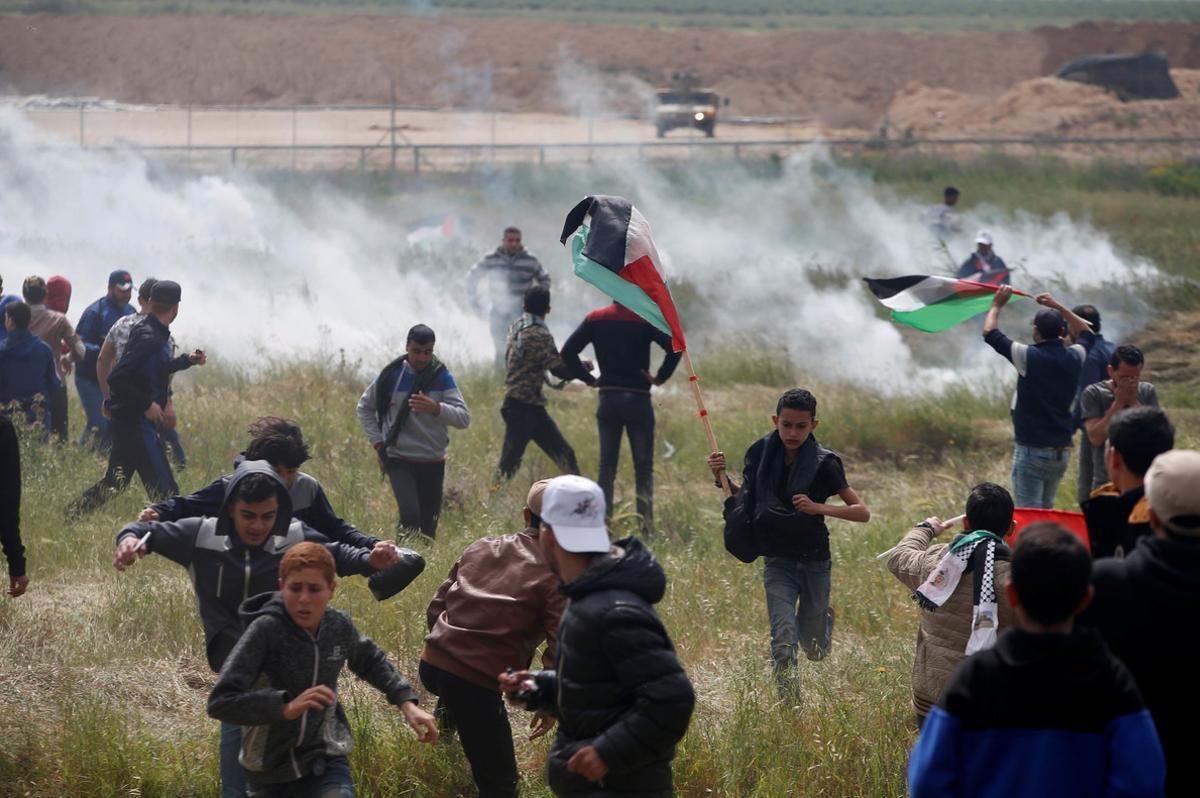 Palestinians run from tear gas fired by Israeli troops during clashes, during a tent city protest along the Israel border with Gaza, demanding the right to return to their homeland, east of Gaza City March 30, 2018. REUTERS/Mohammed Salem