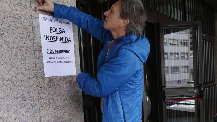 Un trabajador coloca un cartel en el que avisa de la huelga indefinida.